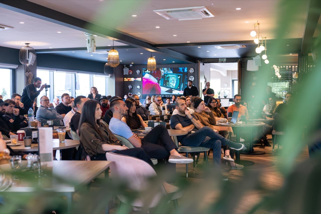 The room at the flagship AI Week session, with 120+ people watching live